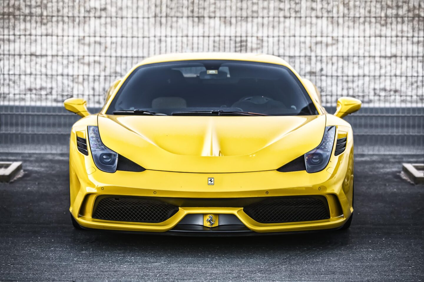 Front view of a yellow Ferrari Italia 458 Special Edition sports car parked on asphalt, photographed by Ahsan Ali Shahid.