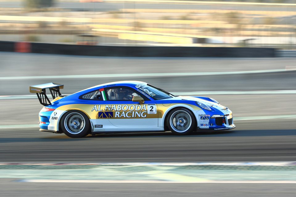 Al Nabooda Racing Porsche 911 GT3 Cup car speeding on a race track, photographed by Ahsan Ali Shahid of AHSANZ Digital.